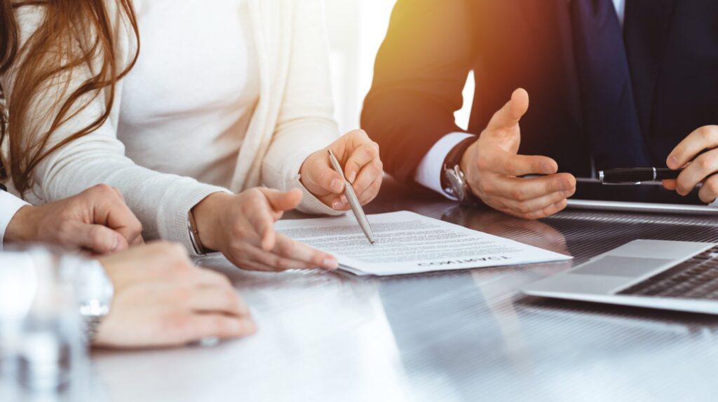 Three people sitting at a desk going over paperwork