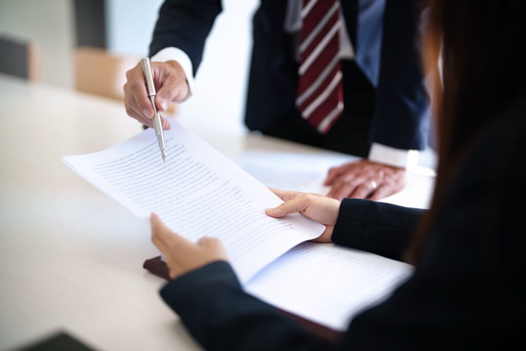 Two sets of hands one holding documents and one holding a pen going over documents