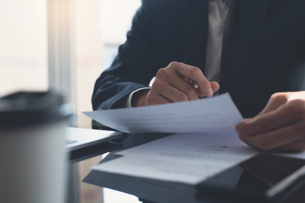 Person sitting at desk going over paperwork and holding a pen