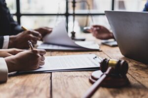 Zoomed in picture of three people sitting at a desk going over paperwork with pens in their hands
